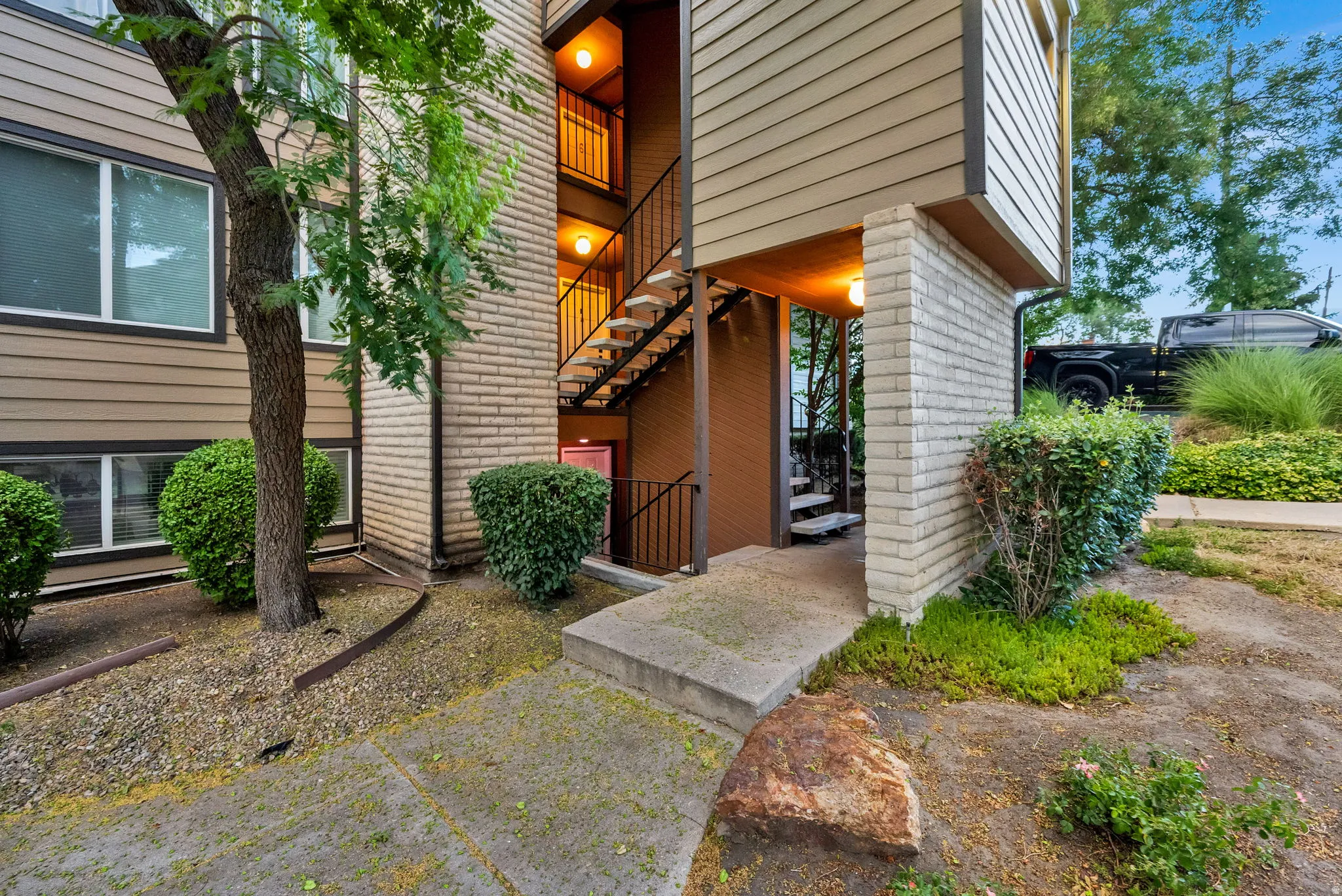 Multi-level building exterior featuring tan siding and light brick accents