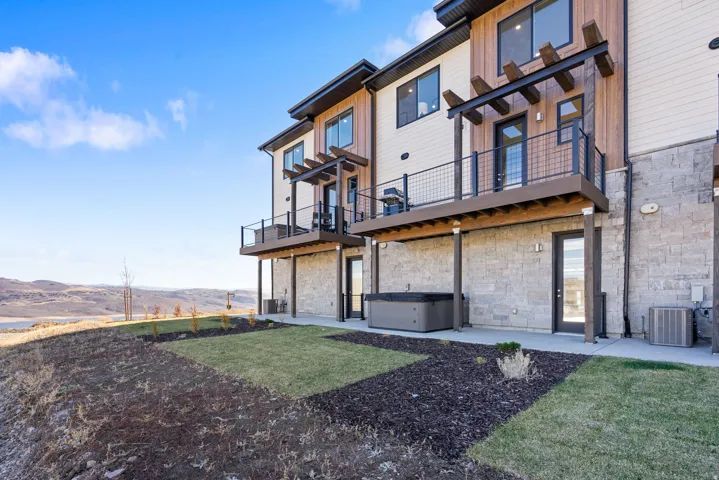 Stone block and wood-finish exterior with a private patio featuring a built-in spa