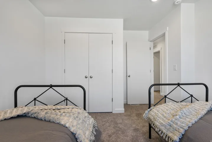 Bedroom featuring neutral wall paint, gray carpet, double-door closet, and white trim