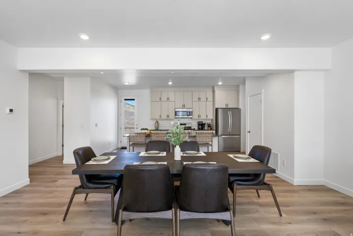 Open-concept dining area featuring wood-finish flooring, recessed lighting, and a neutral color palette