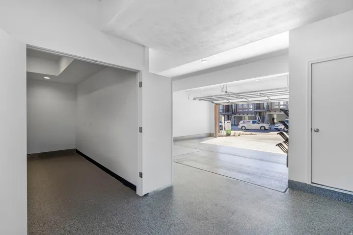 Spacious garage featuring a roll-up door, epoxy flooring, and recessed lighting