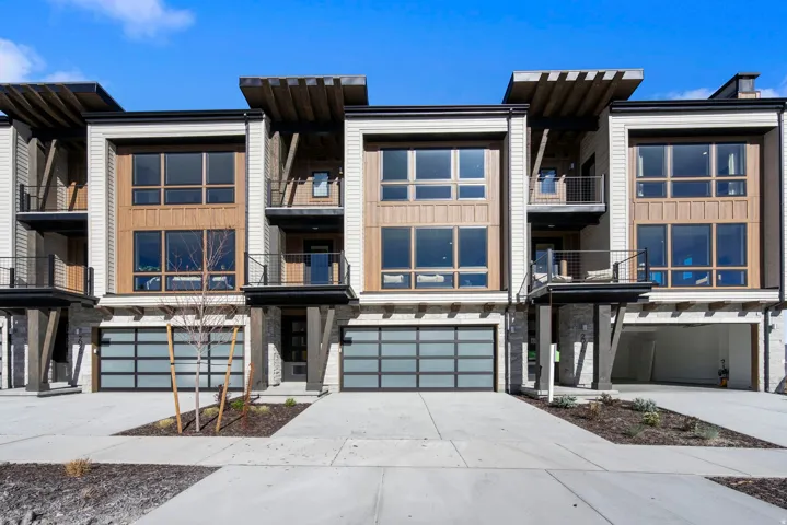 Modern townhome exterior featuring vertical siding, wood-finish paneling, and stone accents