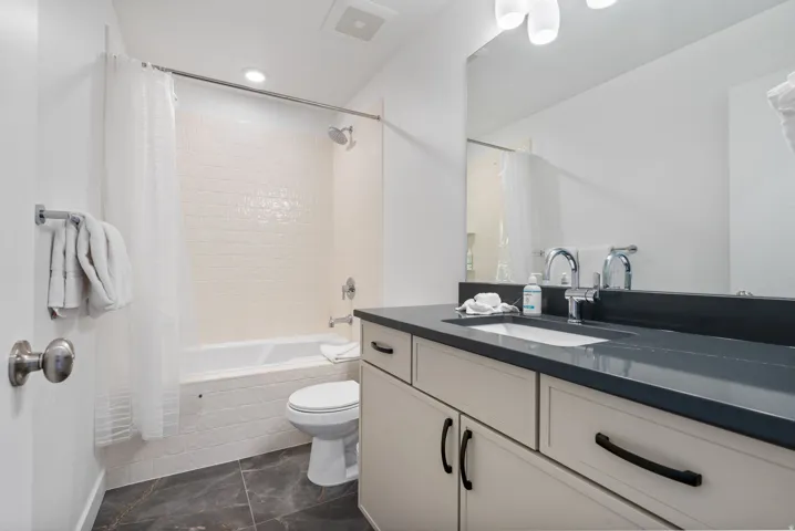 Bathroom featuring a vanity with an integrated sink, dark countertop, and light cabinetry with dark hardware