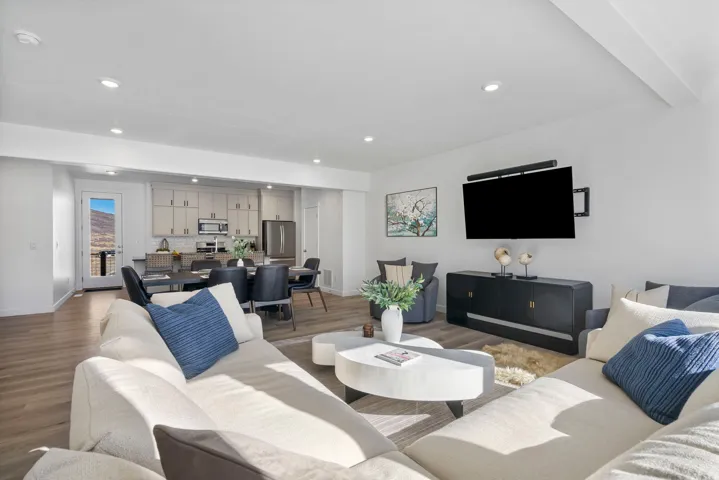 Open-concept living space featuring wood-finish flooring, recessed lighting, and a white color palette