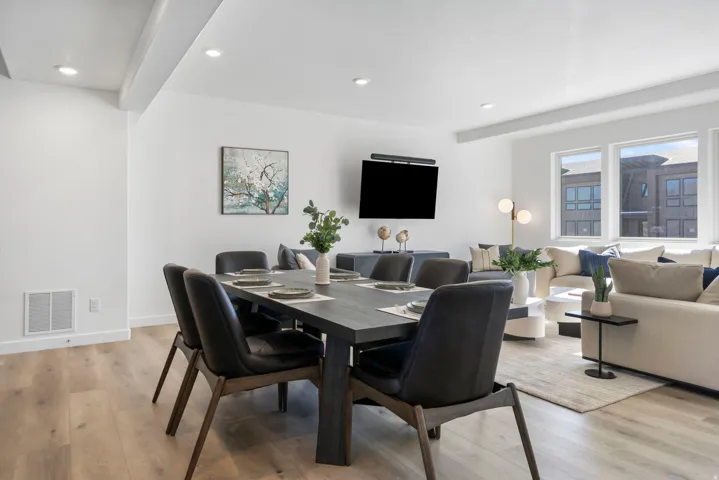 Open-concept living space with light wood-finish flooring, recessed lighting, and large windows
