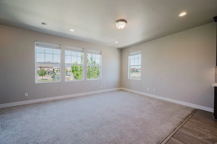 Spacious room featuring multiple windows, recessed lighting, a ceiling-mounted light fixture, light gray carpeting, and light gray wall paint