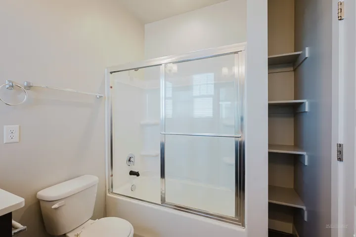 Full bathtub with sliding glass shower doors, white subway tile surround, and chrome fixtures
