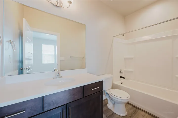 Bathroom featuring a dark wood-finish vanity with a light countertop, integrated sink, and an expansive wall mirror