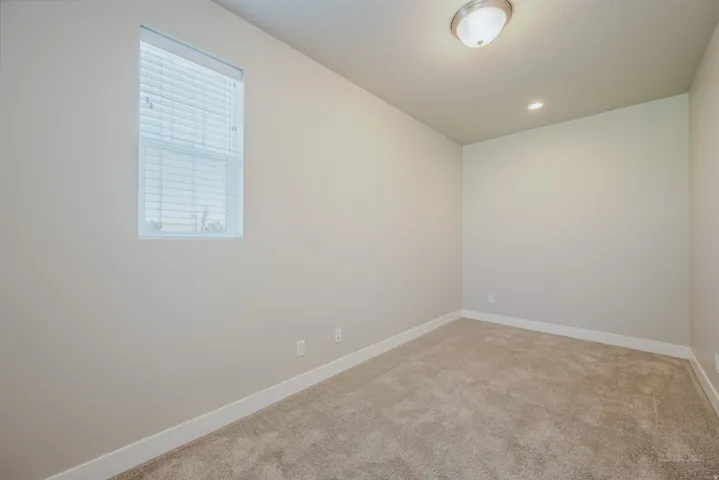 Carpeted room featuring a single window with horizontal blinds, overhead flush mount lighting, and recessed ceiling lighting