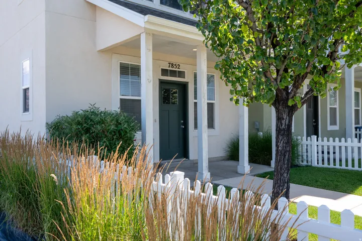 White picket fence enclosing a landscaped front yard with a mature tree