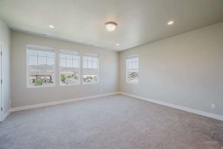 Bright room featuring four large windows, neutral-toned carpet, recessed lighting, and a semi-flush mount ceiling fixture