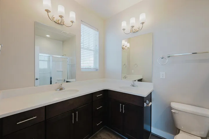 Double vanity with integrated sinks and dark wood-finish cabinetry