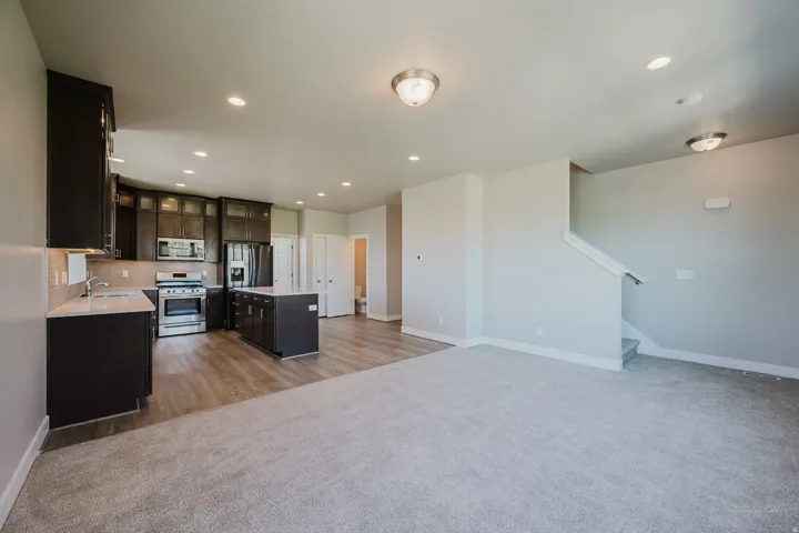 Open-concept living space featuring a modern kitchen with dark wood cabinetry, stainless steel appliances, and a central island