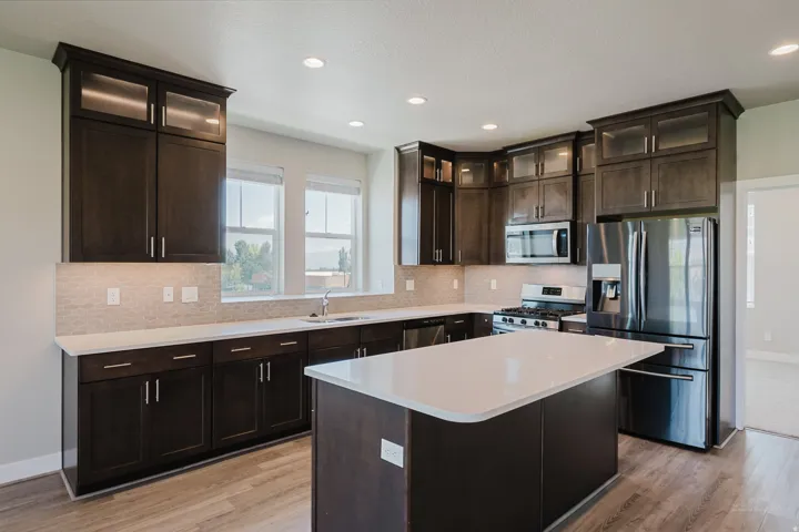 Modern kitchen featuring dark wood cabinetry, white countertops, stainless steel appliances, a center island, and wood-finish flooring