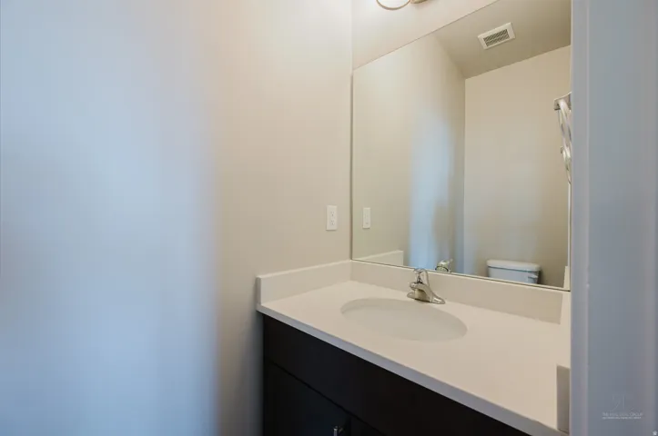 Vanity featuring a white countertop with an integrated sink and chrome faucet