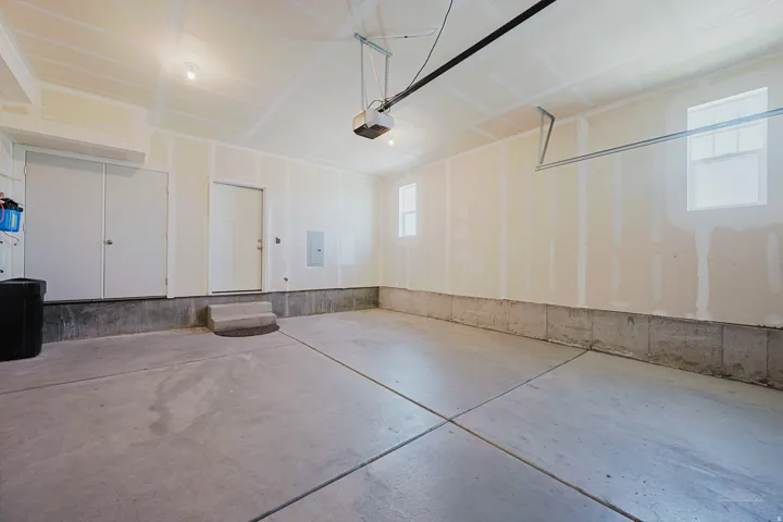 Spacious garage featuring a concrete floor, two windows providing natural light, overhead lighting, and an automatic garage door opener