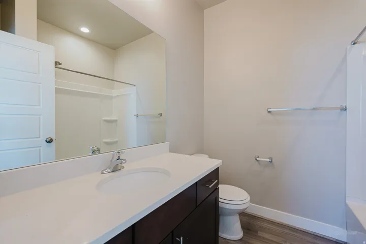 Bathroom featuring a dark wood-finish vanity with an integrated white sink and a light-toned countertop