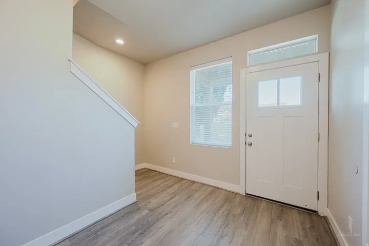Entryway featuring wood-finish flooring, a white front door with clear glass panels, a side window with blinds, and recessed lighting