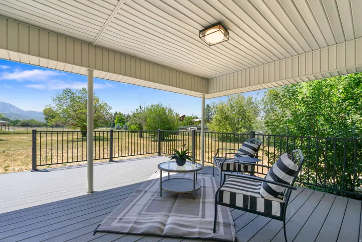 Covered patio featuring a slatted ceiling, recessed lighting, composite decking, and metal railings overlooking natural scenery