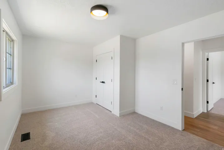 Carpeted room featuring a window with paneled glass, a flush-mount ceiling light fixture, and two white panel doors with black hardware