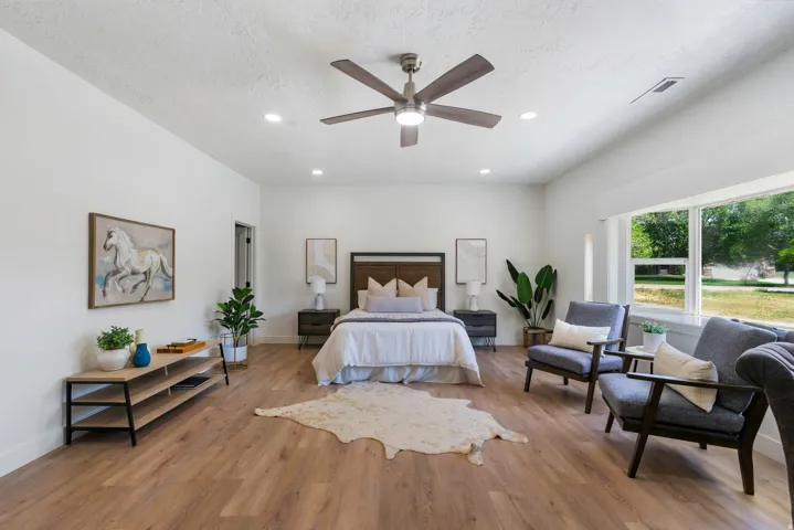 Spacious room featuring wood-finish flooring, a contemporary ceiling fan, recessed lighting, and expansive windows