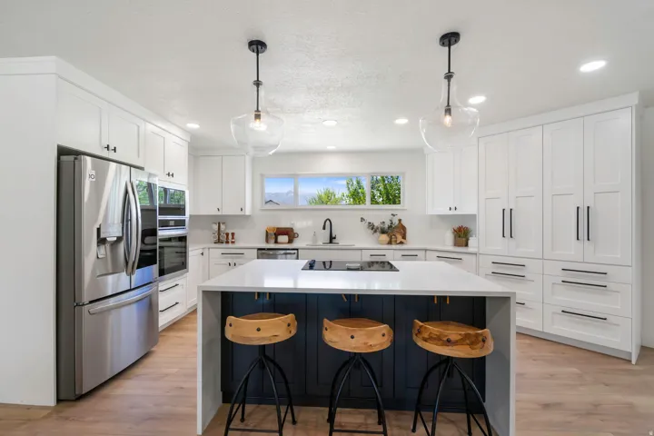 Kitchen featuring white cabinetry, a large center island with seating, stainless steel appliances, wood-finish flooring, and pendant lighting