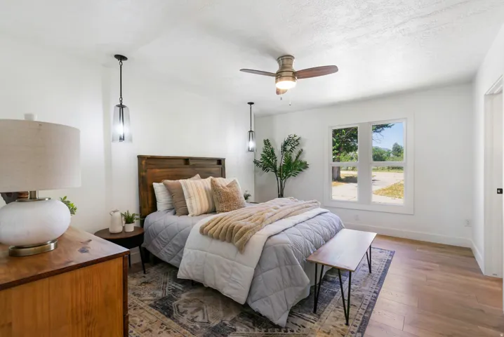 Bedroom featuring wood-finish flooring, a ceiling fan, and white walls