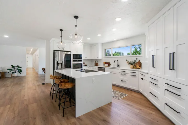 Open-concept kitchen featuring an oversized island with seating, a smooth cooktop, and quartz countertops