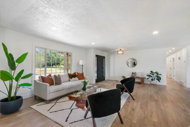 Open-concept living space featuring wood-finish flooring, recessed lighting, and a large picture window with grid detailing