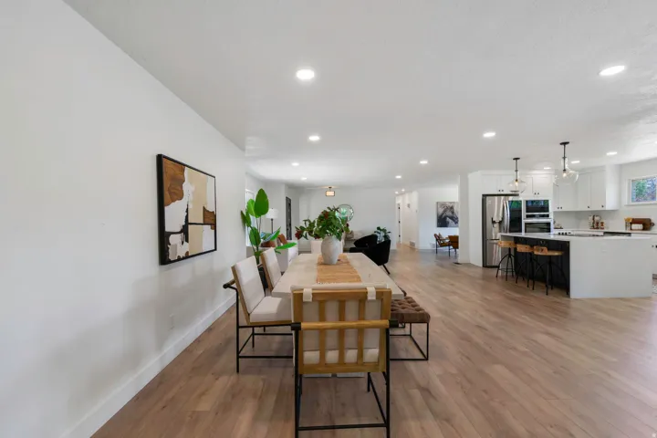 Open-concept living space featuring wood-finish flooring, recessed lighting, and a white color palette