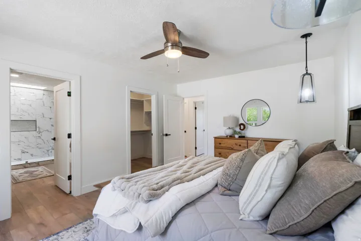 Bedroom with wood-finish flooring, a ceiling fan with integrated lighting, and a contemporary pendant light fixture