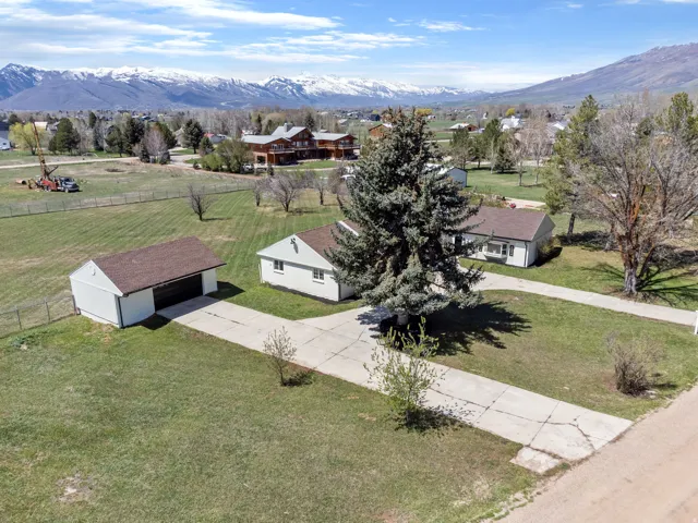 Property featuring a detached garage, expansive green lawn, and concrete driveway