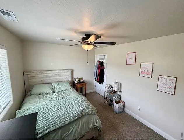 Carpeted room featuring a ceiling fan with integrated lighting, a window with horizontal blinds, a white door frame, and light-toned wall paint