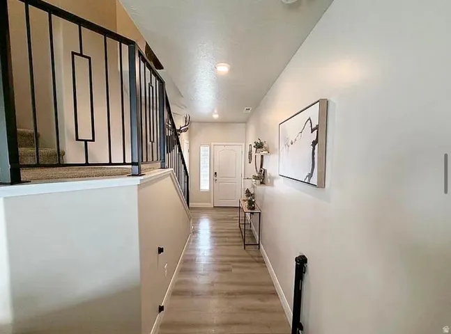 Entryway featuring wood-finish flooring, recessed lighting, and a white paneled door with a sidelight
