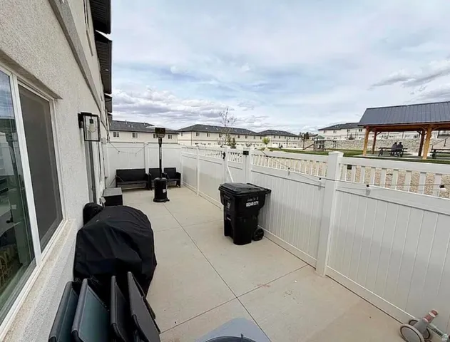 Private concrete patio area with exterior wall sconce lighting and white vinyl fencing
