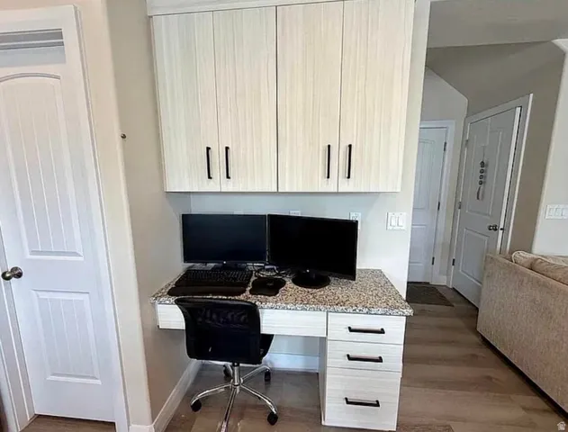 Integrated desk station featuring a speckled countertop, three lower drawers with black hardware, and two upper cabinets with black hardware