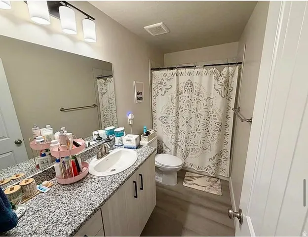 Full bathroom featuring a single vanity with a solid surface countertop, an undermount sink, and a chrome faucet
