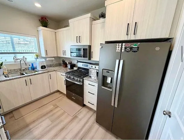 Kitchen featuring light-toned cabinetry with dark hardware, granite countertops, and wood-finish flooring