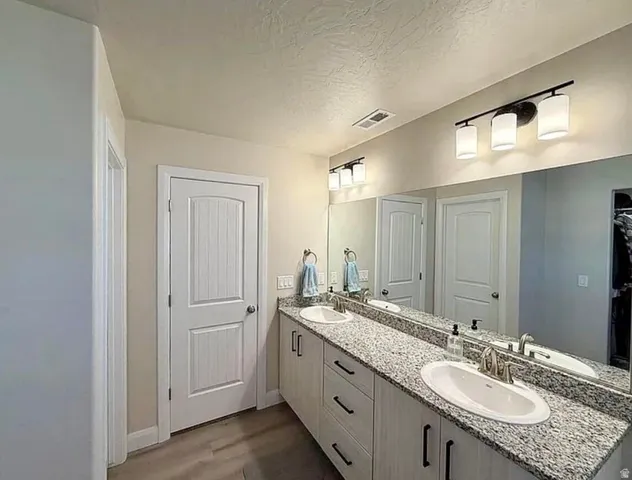 Bathroom featuring a double vanity with granite countertops, undermount sinks, and contemporary light fixtures