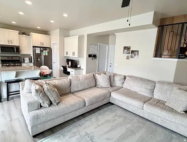 Open-concept living area featuring wood-finish flooring, a kitchen island with seating, recessed lighting, and a built-in desk area