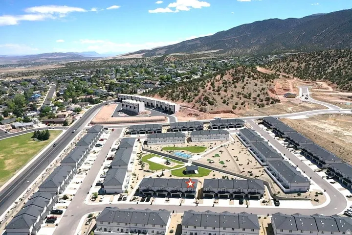 Aerial view of a contemporary townhome community featuring multiple rows of residential units with dark gray roofs