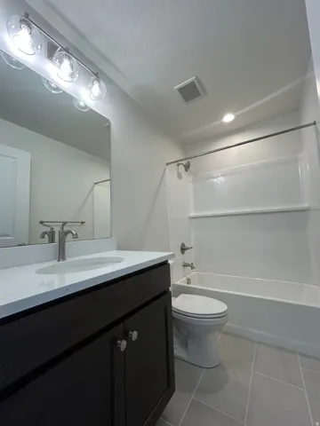 Bathroom featuring a dark wood-finish vanity with a white countertop and undermount sink, brushed nickel faucet, and overhead vanity lighting