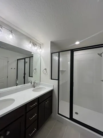 Bathroom featuring a dual vanity with dark wood-finish cabinetry, light-toned countertops, and dual undermount sinks