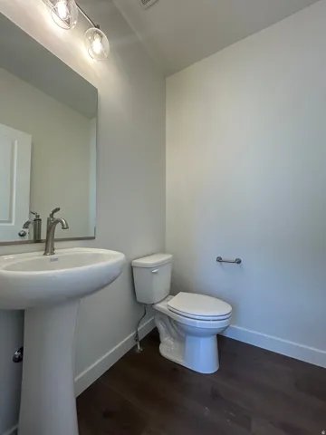 Pedestal sink with brushed nickel faucet, mirror, and track lighting