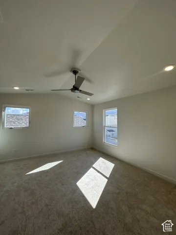 Carpeted room featuring multiple windows, a ceiling fan, and recessed lighting