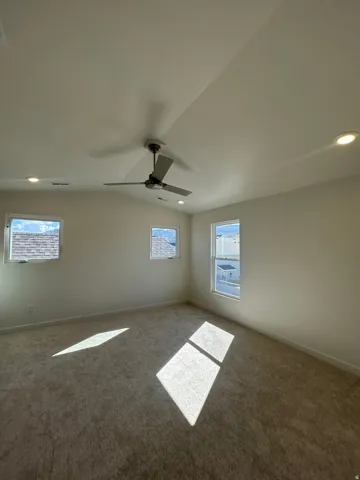 Carpeted room featuring multiple windows, a ceiling fan, and recessed lighting