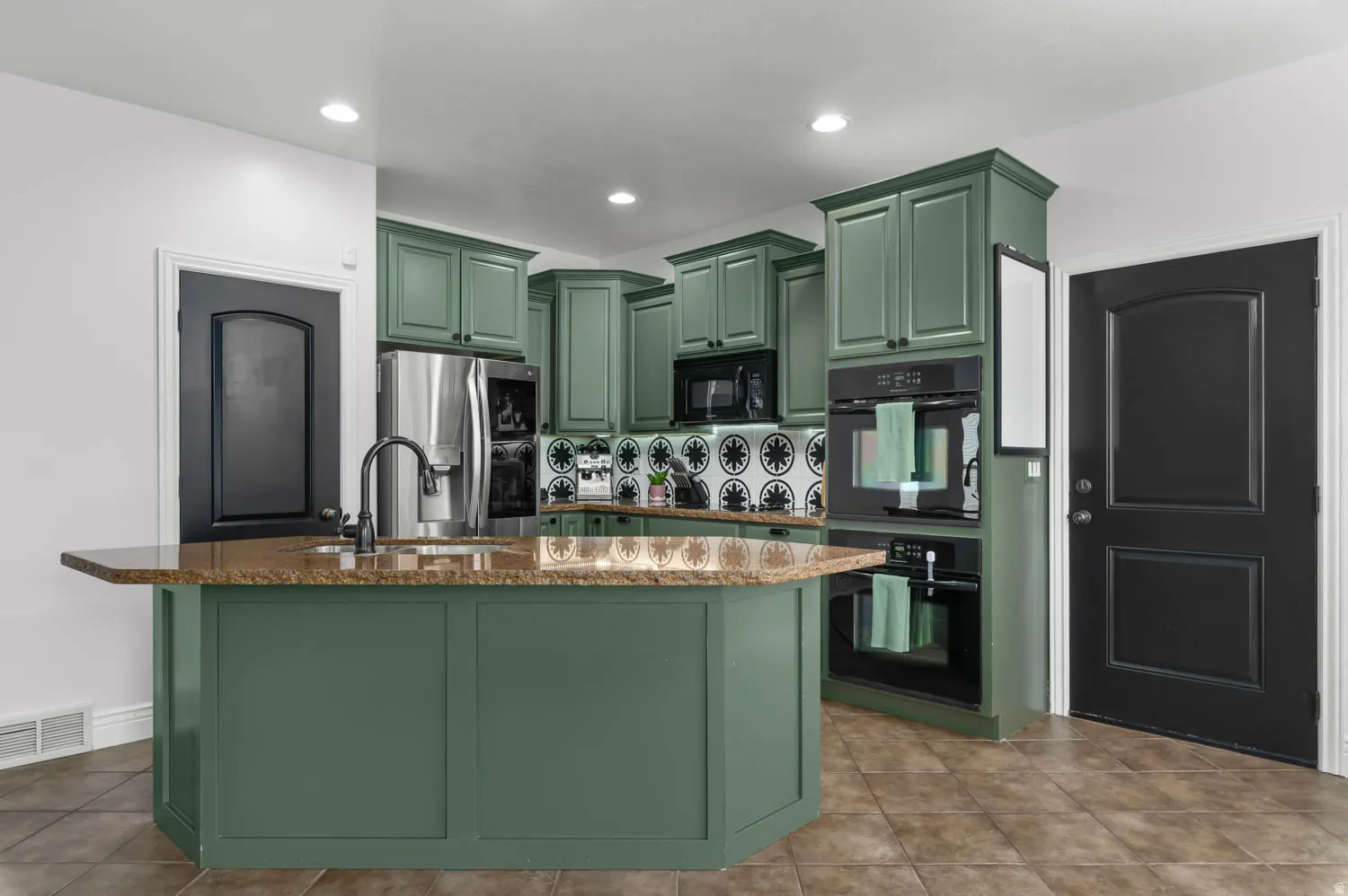 Kitchen featuring a central island with a sink and a patterned tile backsplash