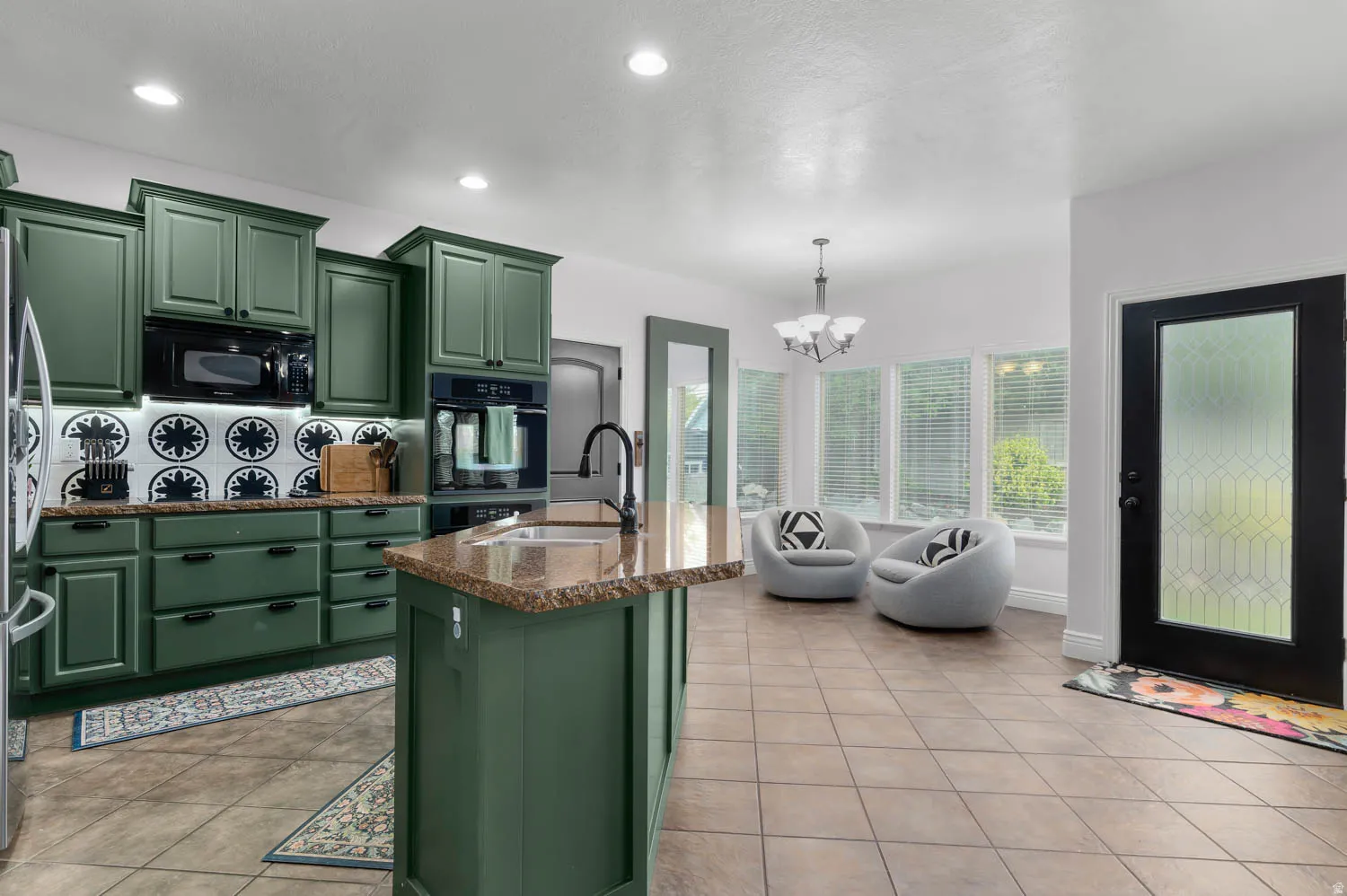 Kitchen featuring olive green cabinetry, built-in appliances, and a central island with a sink