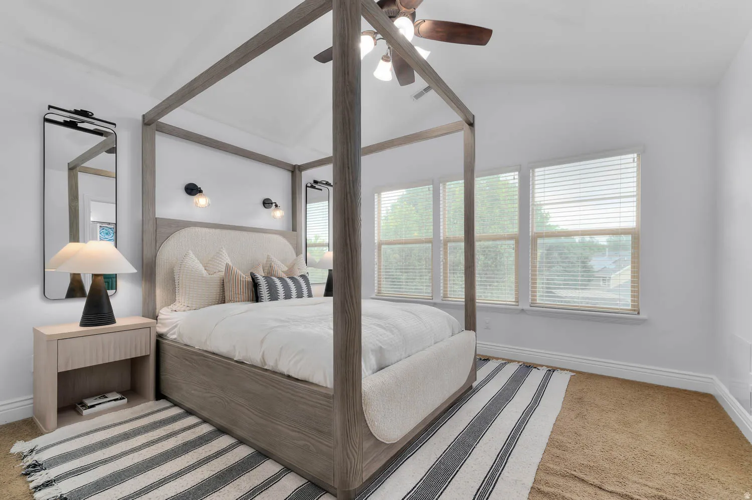 Vaulted ceiling bedroom featuring multiple windows with blinds, a ceiling fan, and sconce lighting