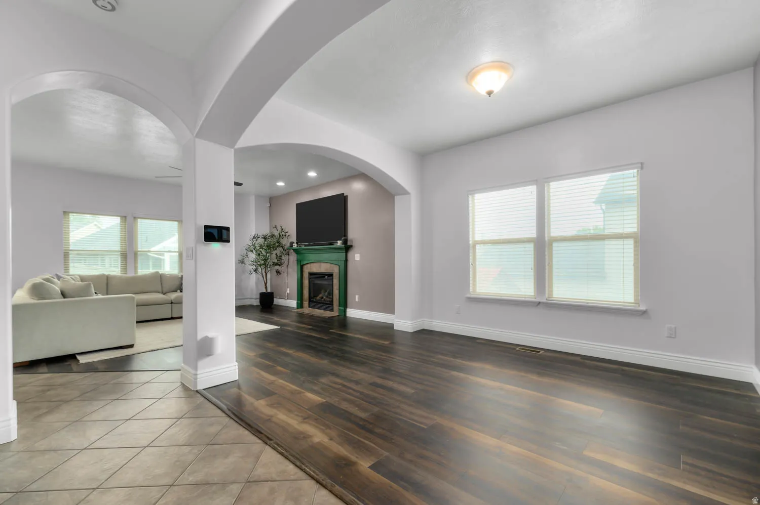 Expansive interior featuring dark wood-finish flooring, arched entryway, and a fireplace with a green-painted mantel